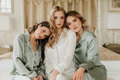 three beautiful women sitting on top of a bed in matching pajamas and slip - ons