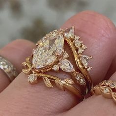 a close up of a person's hand with two rings on their fingers and one ring in the shape of a leaf