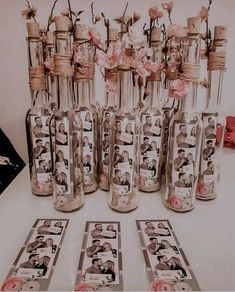 a table topped with vases filled with flowers next to cards and pictures in glass bottles