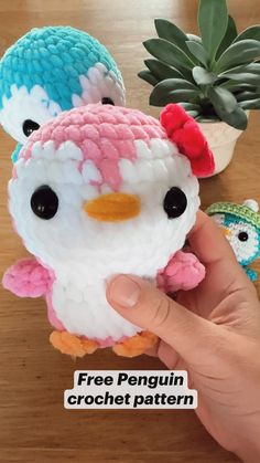 a hand holding a small crochet penguin with flowers on it's head