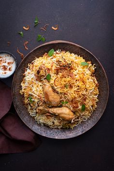 an overhead view of a plate of food with rice and chicken on it, next to a small bowl of sauce