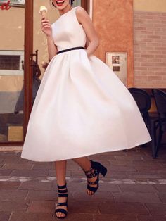 a woman in a white dress is holding an ice cream cone and posing for the camera