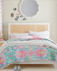 a bedroom with a bed, dresser and mirror on the wall next to it is decorated in pastel colors