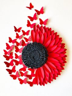 red and black paper butterflies are arranged around a sunflower in the shape of hearts