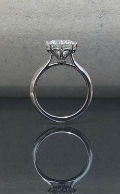 a diamond ring sitting on top of a reflective surface