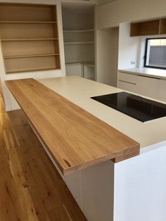 an empty kitchen with white counter tops and wooden flooring, along with built - in shelves