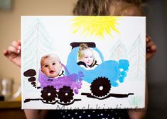 a child holding up a drawing of a train with two children on it's side