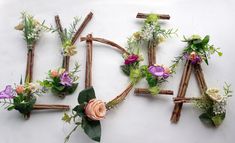 flowers are arranged in the shape of letters made out of sticks and twigs with leaves