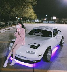 a woman sitting on the hood of a white sports car