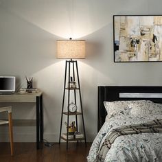 a bedroom with a bed, desk and lamp in it's centerpiece next to a painting on the wall