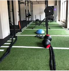 an indoor gym with artificial turf and exercise balls on the ground in front of windows