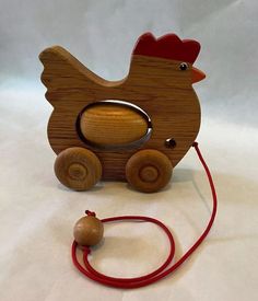 a wooden toy with a red string attached to it and a chicken on the front