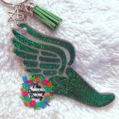 a green keychain with an angel wing and tassel on it's side