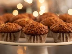 several muffins are on a white plate with lights in the backround