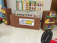 there is a cardboard subway stand in the middle of this room with food on it