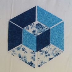 a piece of blue and white fabric with flowers on it that has been cut into hexagonal shapes