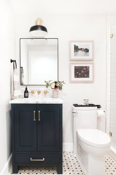 a white and black bathroom with pictures on the wall above the sink, toilet and vanity