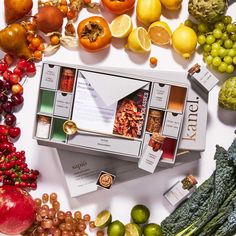 an assortment of fruits and vegetables on a white surface with the box open to show it's contents