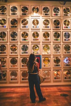 a woman standing in front of a wall full of cds