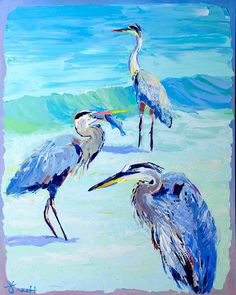 three blue herons are standing in the sand at the water's edge and one is looking for food