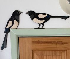 two black and white birds sitting on top of a door