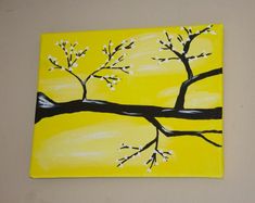 a painting of a tree with white flowers painted on yellow paper, hanging on the wall