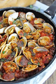 a pan filled with clams and sauce on top of a table