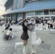 two people are dancing in front of a building with lots of people around them and on the ground