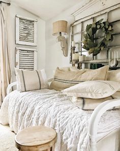 a white bed sitting in a bedroom next to a wooden table and window sill