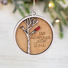 a christmas ornament with a tree and a bird on it that says i am always with you