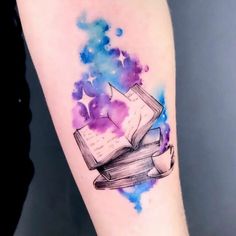 a watercolor tattoo with an open book and stars on it's left arm