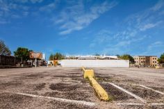 an empty parking lot with buildings in the background