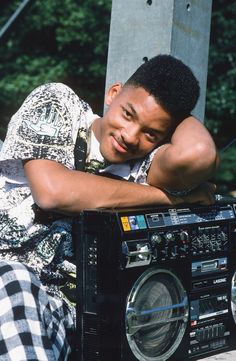 a young man leaning on a boombox with his arms resting on it's head