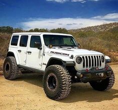 a white jeep is parked in the dirt