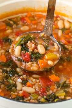 a spoon full of soup with beans and spinach