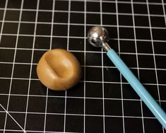 a toothbrush sitting on top of a black counter next to a ball and spoon