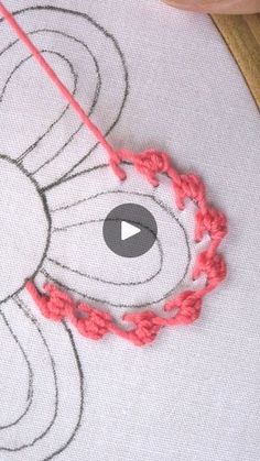 someone is stitching on the fabric with an orange thread and red crochet