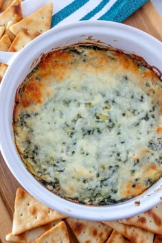 a white bowl filled with spinach dip surrounded by crackers