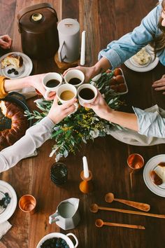 several people are sitting at a table with coffee and pastries on the table top