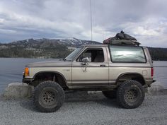 the truck is parked by the water and mountains