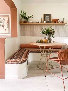 a table with two chairs and a bench in a room that has shelves on the wall