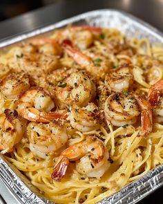 a pan filled with shrimp and pasta on top of a table