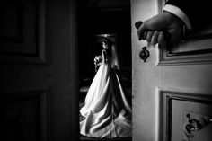 a woman in a wedding dress standing next to a door with her hand on the door handle