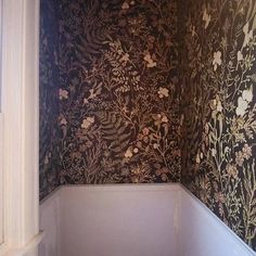 an empty bathroom with floral wallpaper on the walls and toilet in the bathtub