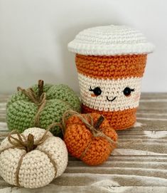 two crocheted pumpkins, one with a coffee cup on it and the other with a smiling face