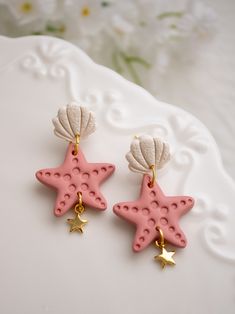 two pink starfish shaped earrings on top of a white plate