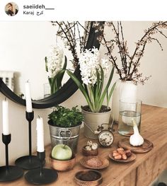 a wooden table topped with vases filled with flowers and other items next to a mirror