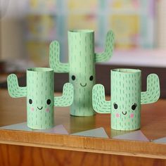 some paper cups with faces on them sitting on a table next to a cactus plant