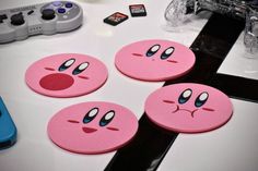 four pink coasters sitting on top of a table next to a video game controller