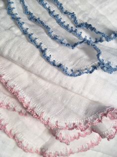 three pieces of cloth with blue and pink crocheted trims on top of each other